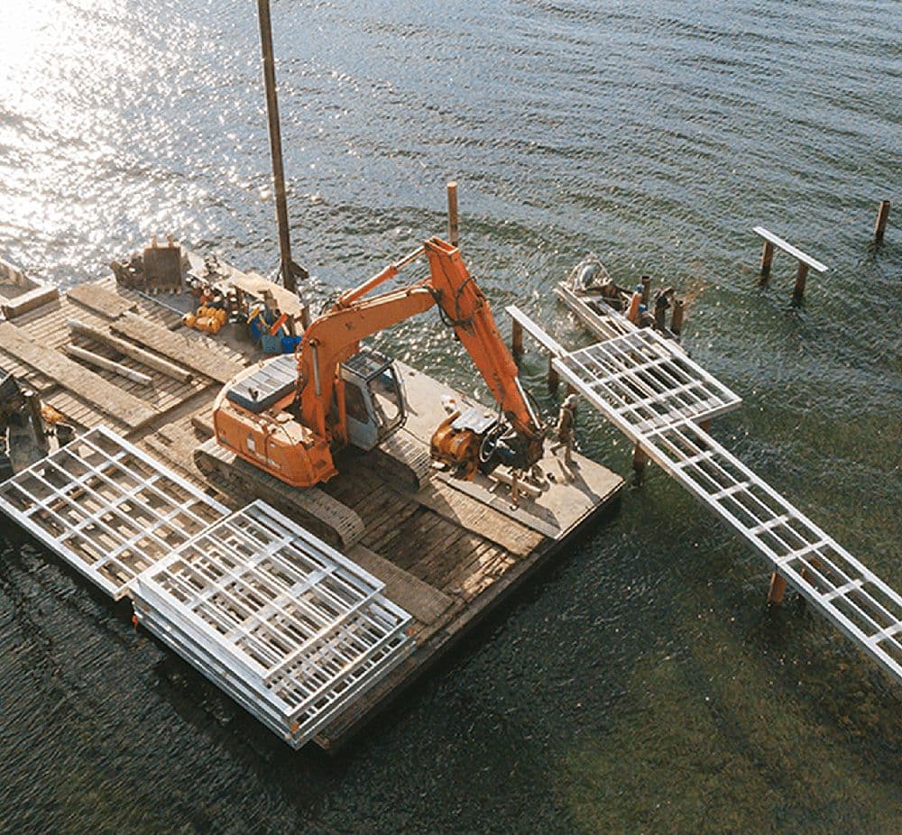 Marina barge and crane on lake replacing old dock with new aluminum dock.